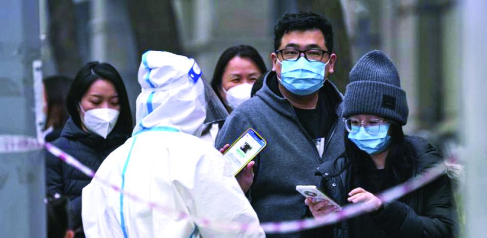 Un hombre muestra su código QR de control de salud mientras él y otras personas hacen fila para hacerse pruebas de rutina de COVID-19 en Pekín, China, el 24 de noviembre de 2022. AP