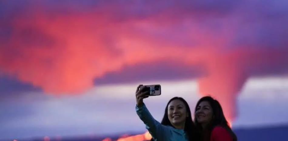 Ingrid Yang, izquierda, y Kelly Bruno, ambos de San Diego, toman una foto frente a la erupción de lava del volcán Mauna Loa de Hawái el miércoles 30 de noviembre de 2022, cerca de Hilo, Hawái. (Foto AP)