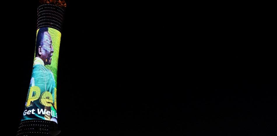 Una imagen tomada el 3 de diciembre de 2022 en Doha, durante el torneo de fútbol Qatar 2022, muestra la torre de la Antorcha de Doha, también conocida como la Torre Aspire, iluminada por una pantalla que representa al astro brasileño Pelé y en la que se lee un mensaje de apoyo al exfutbolista brasileño. Foto: Patricia de Melo Moreira/AFP.