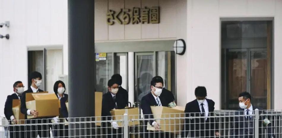 Investigadores policiales sacaron cajas con documentos de la guardería Sakura en la ciudad de Susono, Shizuoka, en el centro de Japón, el domingo 4 de diciembre de 2022. La policía arrestó a tres maestras de la guardería que maltrataban a los niños. (Noticias de Kyodo vía AP).