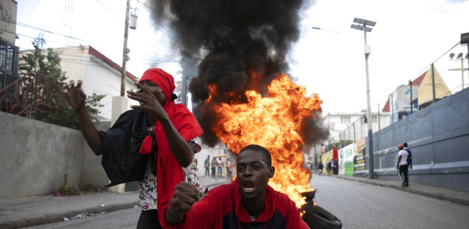 Manifestantes gritan consignas contra el gobierno frente a una barricada de neumáticos en llamas durante una protesta, el viernes 18 de noviembre de 2022, en Puerto Príncipe, Haití. AP