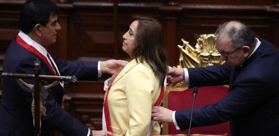 La exvicepresidenta Dina Boluarte recibe la banda presidencial tras prestar juramento como nueva presidenta en el Congreso en Lima, ayer. AP