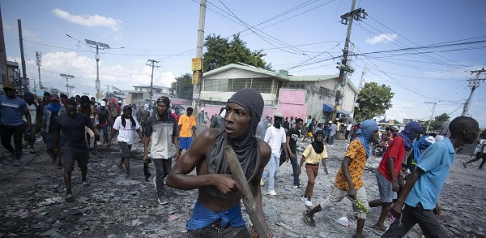 Un manifestante porta un pedazo de madera como si fuera un rifle durante una protesta antigubernamental, el 3 de octubre del 2022, en Puerto Príncipe, Haití. (AP)
