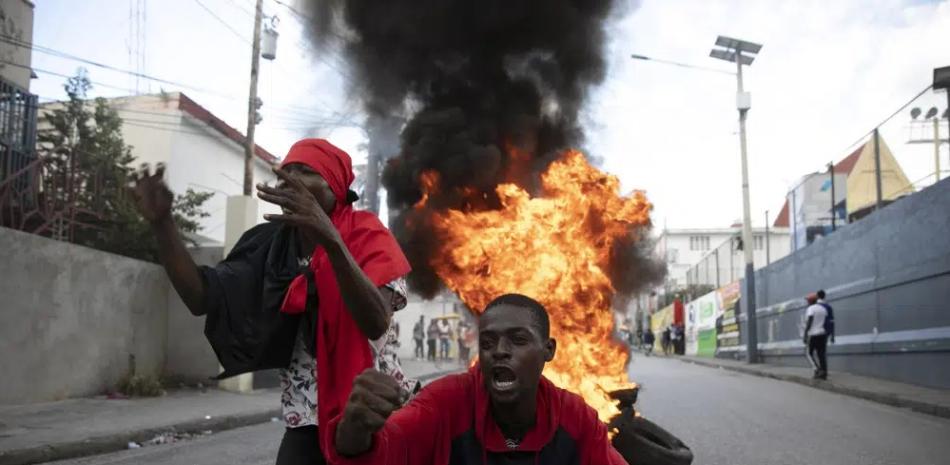 Manifestantes cantan lemas antigubernamentales frente a una barricada de llantas en llamas durante una protesta contra el gobierno en Puerto Príncipe, el viernes 18 de noviembre de 2022. AP