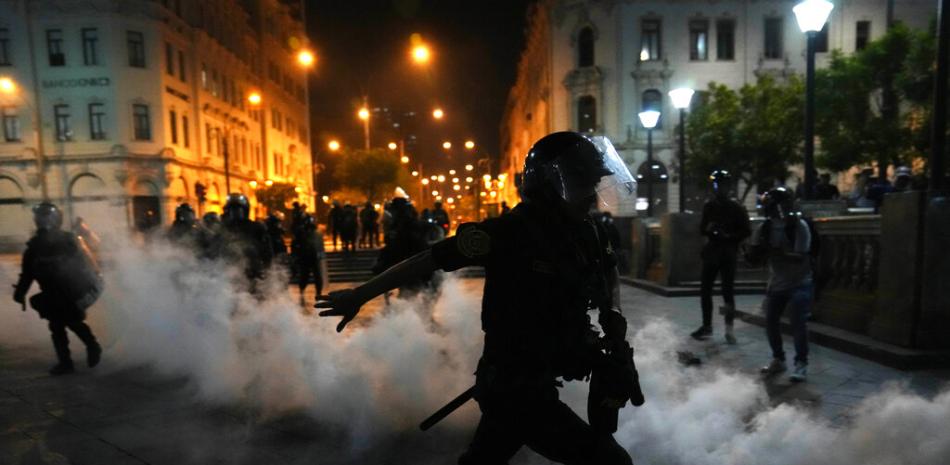 Una nube de gas lacrimógeno rodea a los policías que intentan disipar a simpatizantes del destituido presidente Pedro Castillo, el domingo 11 de diciembre de 2022, en la plaza San Martín, en Lima. (AP Foto/Martín Mejía)