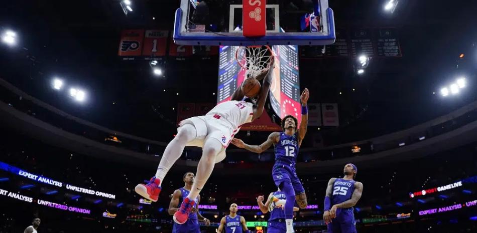 Joel Embiid, de los Sixers, donquea ante Kelly Oubre Jr., de los Hornets, durante la primera mitad del partido del domingo por la noche en el baloncesto de la NBA.
