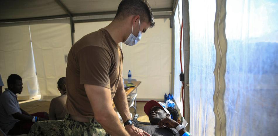 Un hombre es tratado por un equipo médico del buque hospital USNS Comfort en un hospital improvisado junto a un muelle en Jeremie, Haití, el miércoles 14 de diciembre de 2022. (Foto AP/Odelyn Joseph)