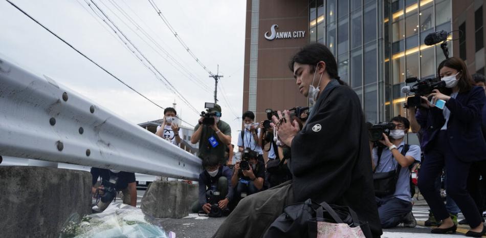 Un hombre reza frente a un monumento improvisado en la escena donde le dispararon al exprimer ministro Shinzo Abe durante una campaña electoral en Nara, oeste de Japón, el viernes 8 de julio de 2022. (Foto AP/Hiro Komae)