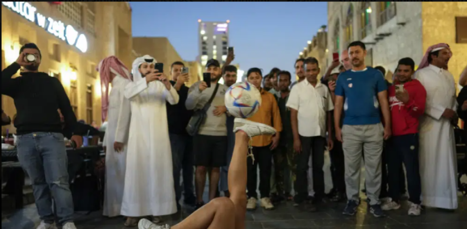 Belén Godoy, de Argentina, hace malabares con una pelota para conseguir el dinero que le permita comprar una entrada de la final del Mundial, en el mercado Souq Waqif de Doha, Qatar, martes 25 diciembre 2022. (AP Foto/Andre Penner)