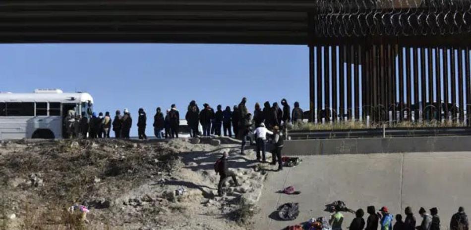 Decenas de migrantes esperan a subir a un autobús del gobierno estadounidense tras cruzar la frontera desde Ciudad Juárez, México, a El Paso, Texas, el 12 de diciembre de 2022. AP