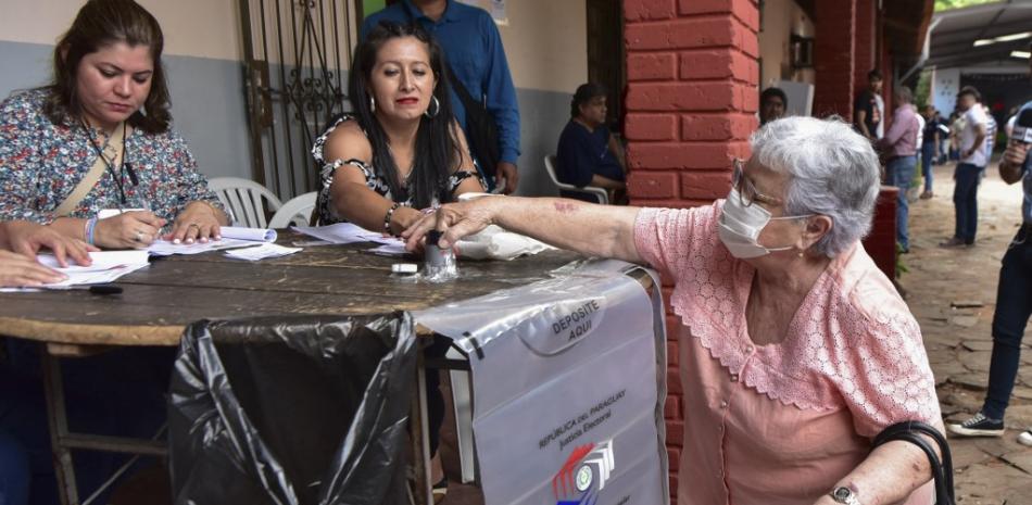 Una mujer deposita su voto durante las elecciones primarias en Asunción, el 18 de diciembre de 2022. Fuente: AFP.