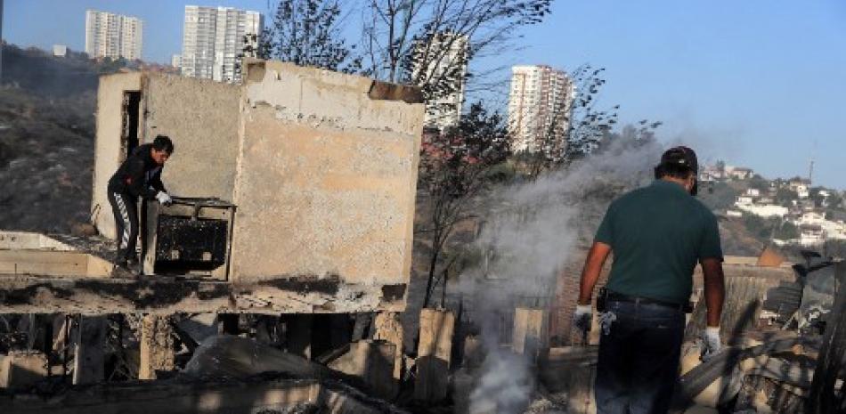 Hombres retiran escombros de casas destruidas por un incendio forestal en los cerros de Viña del Mar, en la región de Valparaíso, Chile, el 23 de diciembre de 2022. AFP