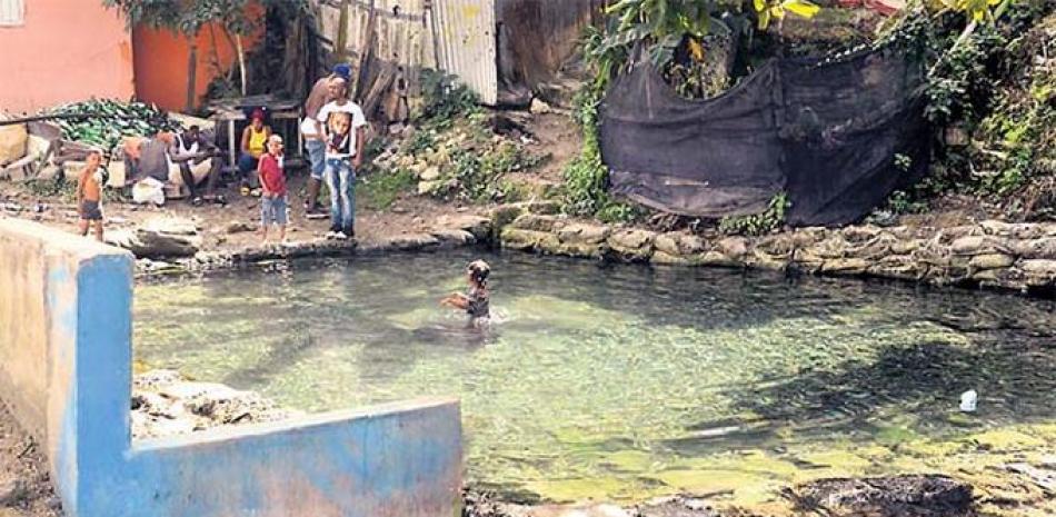 Niños de diferentes edades y personas adultas continúan utilizando el agua del río Isabela en desafío a las medidas sanitarias.