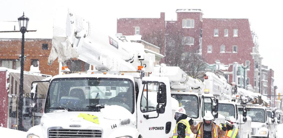 Camiones de líneas eléctricas llegan a Allen Street para suministrar energía a apartamentos y casas en Buffalo, Nueva York, el lunes 26 de diciembre de 2022. Muchas personas se quedaron sin electricidad donde viven debido a la reciente tormenta de nieve. (Joseph Cooke/The Buffalo News vía AP)