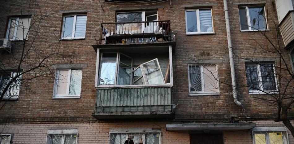 Un residente local repara una ventana rota en un edificio de apartamentos parcialmente destruido por un ataque ruso en la capital ucraniana, Kiev, el 31 de diciembre de 2022. Fuente: AFP.