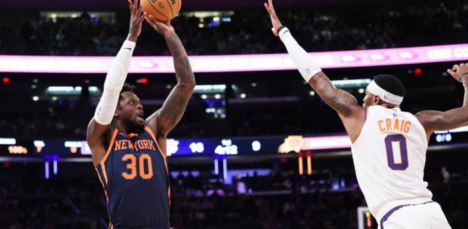 El alero de los Knicks de Nueva York Julius Randle lanza el balón sobre el alero de los Suns de Phoenix forward Torrey Craig.