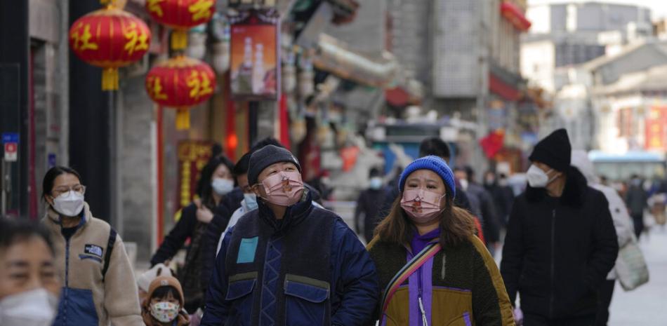 Visitantes con mascarillas recorren una calle comercial peatonal en la calle peatonal Qianmen en Beijing, el martes 3 de enero de 2023.