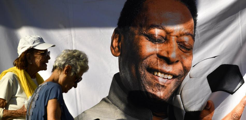 Dos personas hacen fila para entrar al estadio Vila Belmiro para presentar sus respetos a la fallecida leyenda del fútbol Pelé, en Santos, Brasil, el 2 de enero de 2023. (AP Foto/Matías Delacroix)