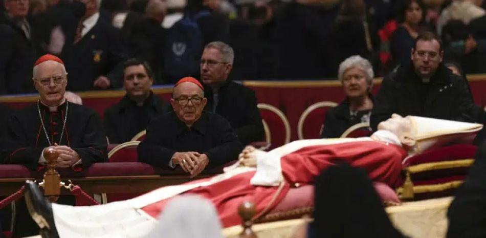 El cardenal Odilo Scherer (izquierda) reza frente al cuerpo del papa emérito Benedicto XVI en la Basílica de San Pedro, en el Vaticano, ayer martes.