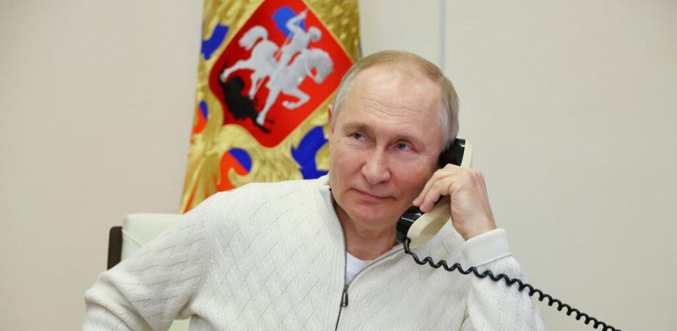 El presidente ruso, Vladimir Putin, habla por teléfono con David Shmelev, de siete años, de la región de Stavropol Krai, participante de la campaña benéfica Fir Tree of Wishes. AP.