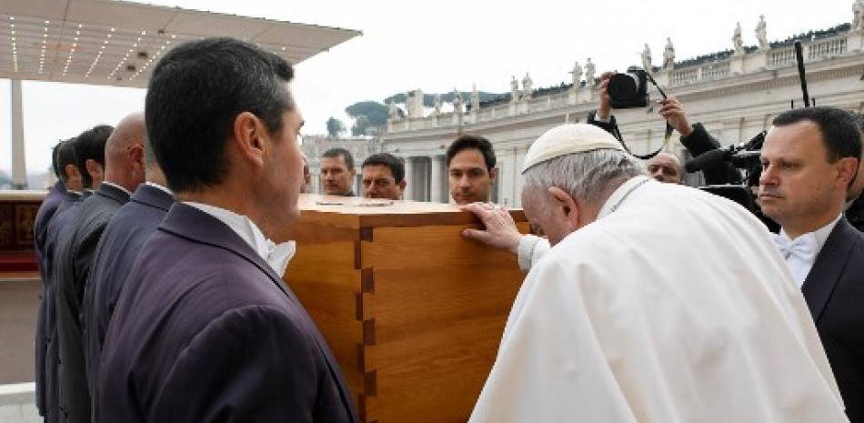Esta foto tomada y distribuida el 5 de enero de 2023 por The Vatican Media muestra al papa Francisco mostrando su respeto al tocar el ataúd del papa emérito Benedicto XVI durante su misa fúnebre en la plaza de San Pedro en el Vaticano. AFP