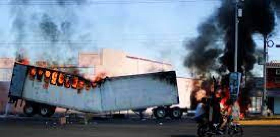 Hombres en motocicleta pasan junto a un camión en llamas en las calles de Culiacán, estado de Sinaloa, el jueves 5 de enero de 2023. Las fuerzas de seguridad mexicanas capturaron a Ovidio Guzmán.