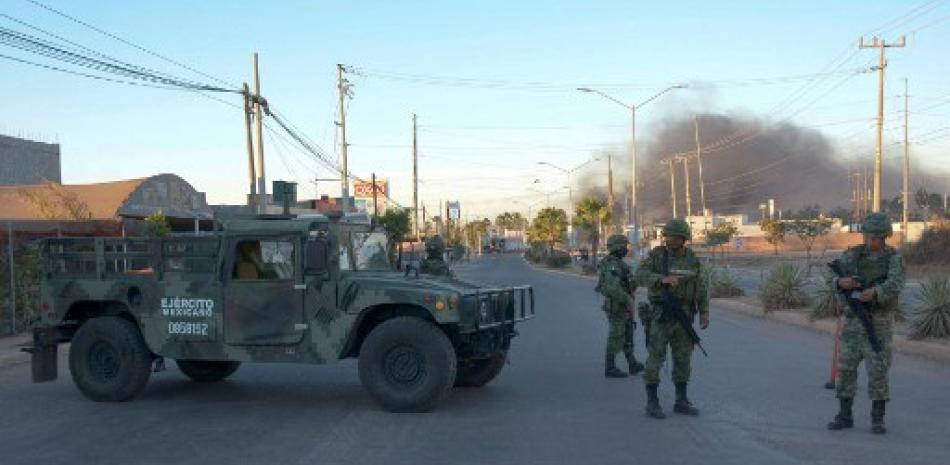Soldados mexicanos montan guardia cerca de vehículos en llamas en una calle durante una operación para arrestar al hijo de Joaquín "El Chapo" Guzmán, Ovidio Guzmán, en Culiacán, estado de Sinaloa, México, el 5 de enero de 2023. AFP