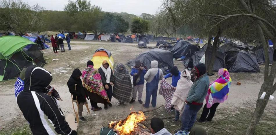 Migrantes soportan un tiempo frío alrededor de una fogata en un campamento improvisado en la frontera entre Estados Unidos y México, el 23 de diciembre de 2022. ap
