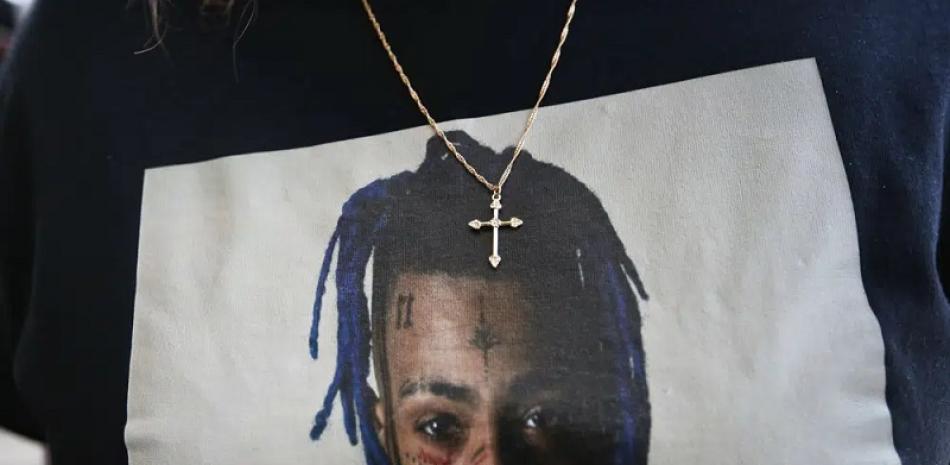 En esta foto de archivo del 27 de junio de 2018, una fan usa una cruz alrededor de su cuello que cuelga de una camiseta en recuerdo antes de ingresar a un memorial para el rapero XXXTentacion en Sunrise, Florida. AP