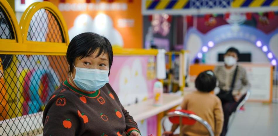 Una mujer con mascarilla usa un teléfono móvil en un centro comercial de Pekín. EFE/EPA/Wu Hao
