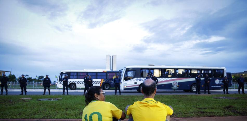 Una pareja de simpatizantes del expresidente Jair Bolsonaro observan el movimiento de agentes de la policía durante una protesta convocada por los decisivos del exmandatario en Brasilia, el miércoles 11 de enero de 2023.

Foto: AP Foto/Gustavo Moreno
