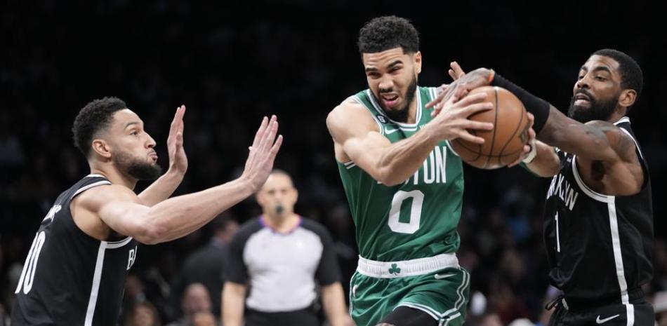 Jason Tatum, de los Celtics, maneja el balón entre la defensa de Ben Simmons y Kyrie Irving, de los Nets, en el partido del jueves por la noche en la NBA.
