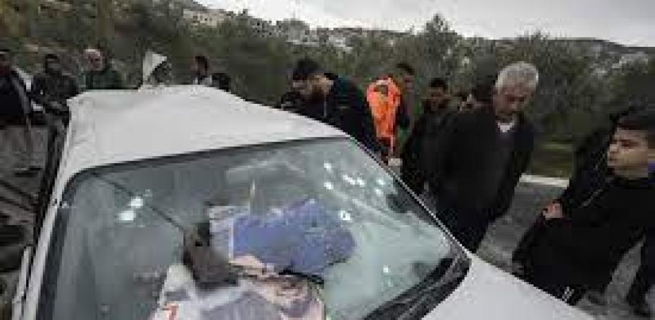 Palestinos revisan un auto dañado tras una redada israelí en la localidad cisjordana de Jaba, el 14 de enero de 2023. Fuente: AP.