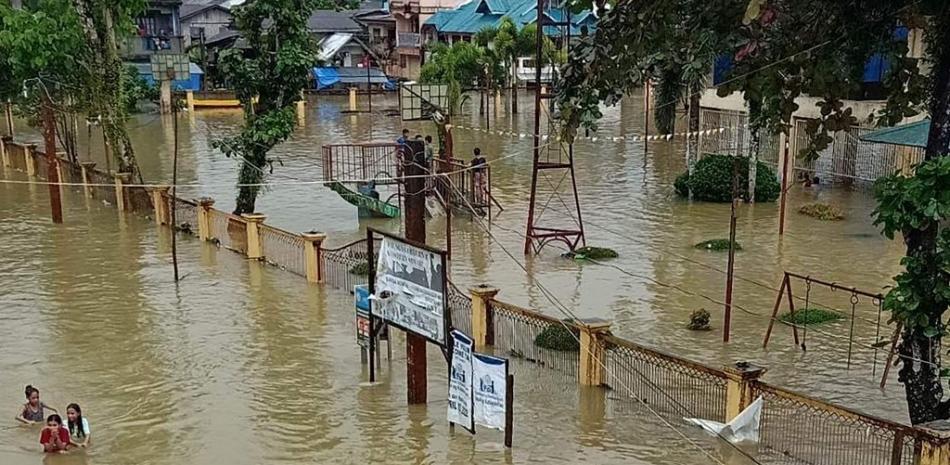 Esta foto tomada el 11 de enero de 2023 y recibida del alcalde de Jipapad, Benjamin Ver, muestra a los residentes vadeando una carretera inundada en la ciudad de Jipapad, provincia de Samar Oriental. Fuente: AFP.