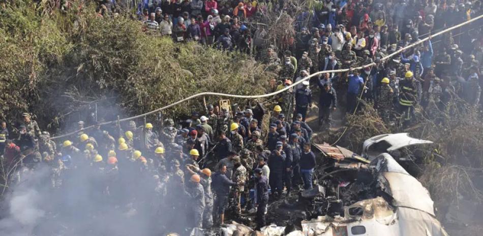 Trabajadores de rescate y civiles nepaleses se reúnen alrededor de los restos de un avión de pasajeros que se estrelló en Pokhara, Nepal, ayer. ap
