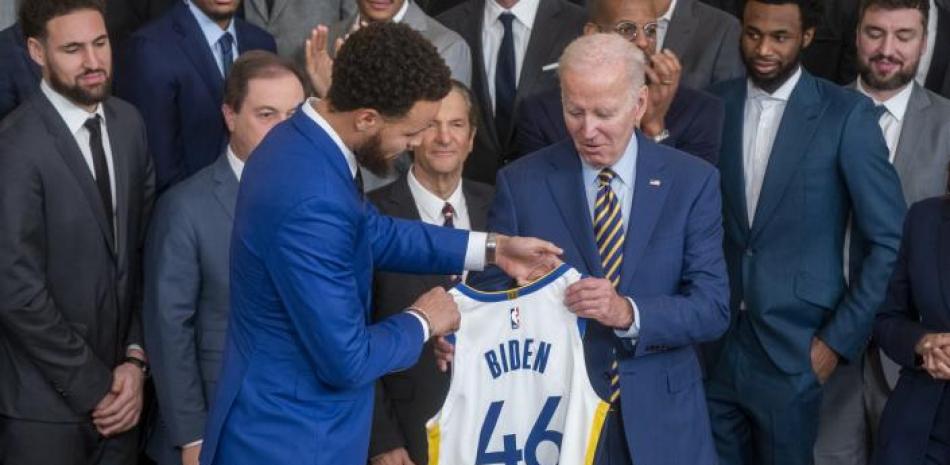 Stephen Curry, de los Warriors, entrega una camiseta del equipo al presidente de los Estados Unidos Joe Biden, en la visita del campeon de la NBA a la Casa Blanca.