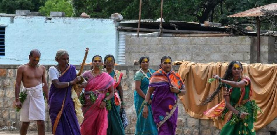 En esta imagen tomada el 21 de septiembre de 2022, una ex mujer 'devadasi' que fue dedicada por su familia a la diosa hindú Yellamma Devi, baila (derecha) mientras otros devotos cantan antes de visitar el templo de Yellamma Devi en Savadatti, en el distrito de Belgaum, en la India.
