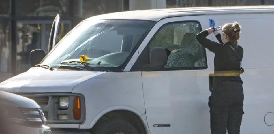 Una fotógrafa forense se prepara para tomar fotos de la ventana de una camioneta en Torrance, California, el domingo 22 de enero de 2023. (AP Foto/Damian Dovarganes)