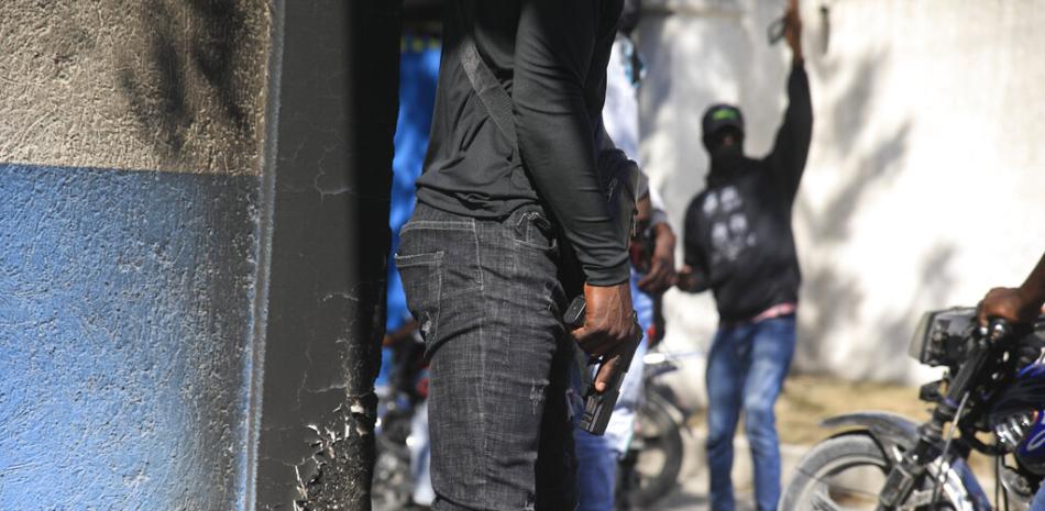 Oficiales de policía armados con las armas desenvainadas frente a la sede de la policía durante una protesta para denunciar el mal gobierno policial, en Puerto Príncipe, Haití, el jueves 26 de enero de 2023. (Foto AP/Odelyn Joseph).