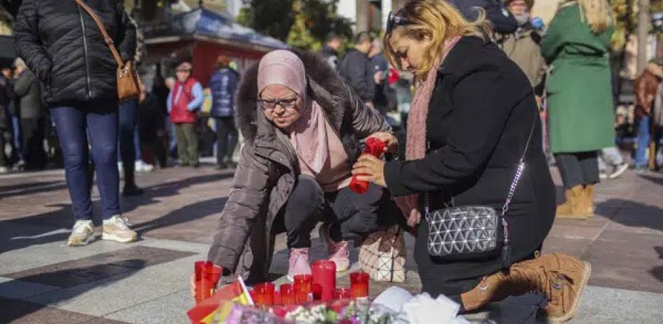 Dos mujeres encienden velas en memoria de un sacristán asesinado el miércoles en Algeciras.  AP