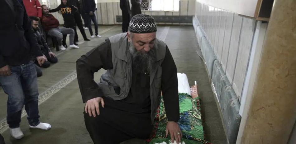 Un pariente hace una pausa después de colocar una alfombra de oración sobre Nassim Abu Fouda en su funeral en Hebrón, Cisjordania, ayer. AP