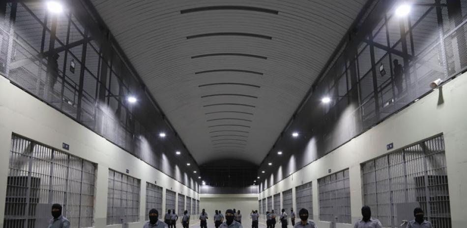 Guardias civiles de la Dirección General de Prisiones se colocan afuera de las celdas en el Centro de Confinamiento del Terrorismo durante una gira de medios en Tecoluca, El Salvador. AP/