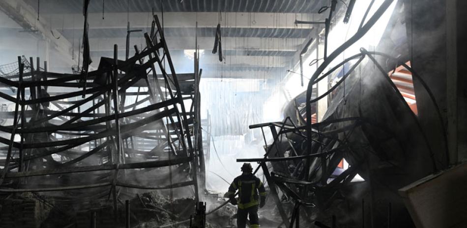 Un bombero ucraniano camina entre los escombros en un centro comercial de ferretería luego de un bombardeo ruso ayer en Kherson.  AFP/