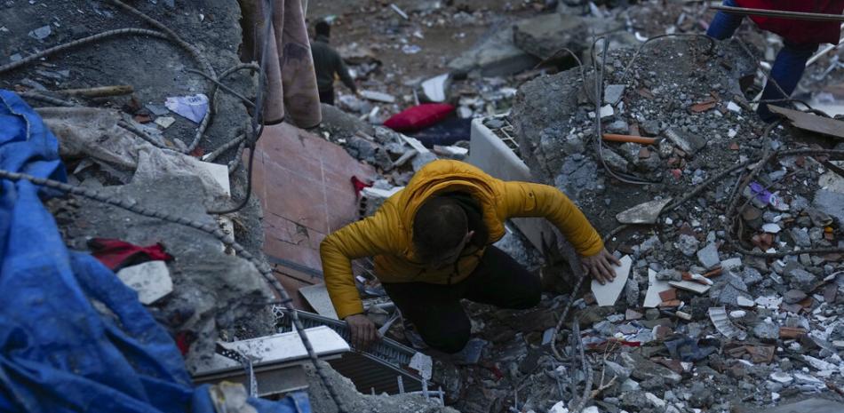Un hombre busca personas en un edificio destruido en Adana, Turquía, el lunes 6 de febrero de 2023. Un poderoso terremoto derribó varios edificios en el sureste de Turquía y Siria y se temen muchas víctimas. (Foto AP/Khalil Hamra)