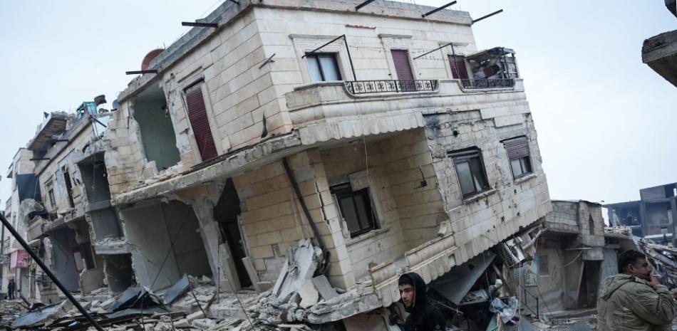 Residentes frente a un edificio derrumbado tras un terremoto en la localidad de Jandaris, en el campo de la ciudad noroccidental siria de Afrin, en la parte de la provincia de Alepo controlada por los rebeldes, el 6 de febrero de 2023. Fuente: AFP.