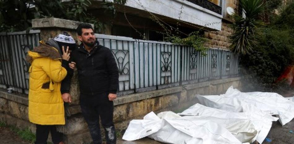 Los sirios reaccionan cerca de los cuerpos cubiertos con plástico que yacen en la calle frente a una morgue en la ciudad de Alepo luego de un terremoto mortal el 6 de febrero de 2023. AFP