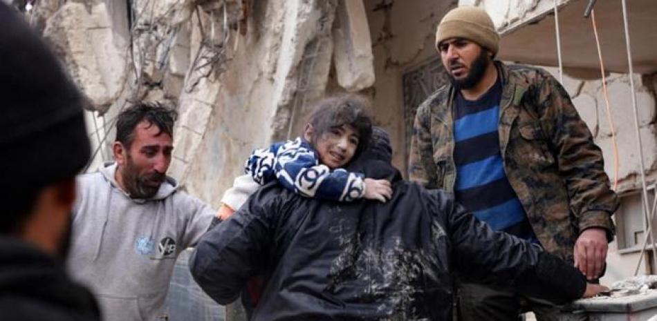 Una niña recibe ayuda para salir de entre los escombros de un edificio derribado por el terremoto en Jandaris, en el noroeste de Siria, el 6 de febrero de 2023 / AFP