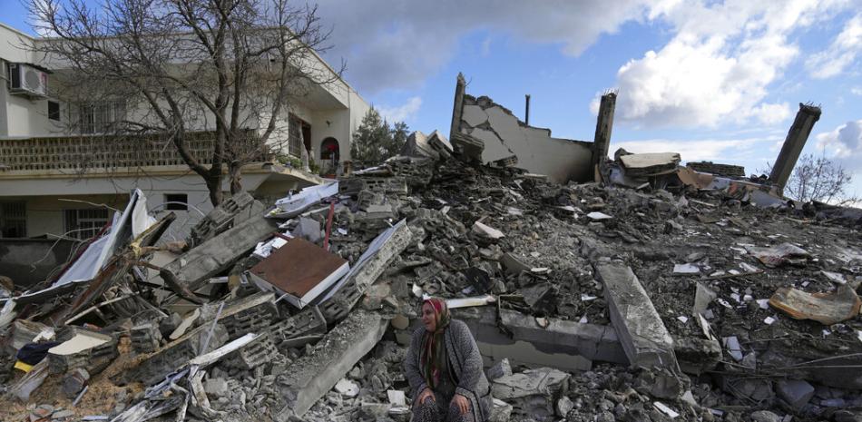 Una mujer está sentada sobre los escombros mientras los equipos de rescate buscan gente debajo de los restos de edificios en la población de Nurdagi, en el sur de Turquía, martes 7 de febrero de 2023. AP