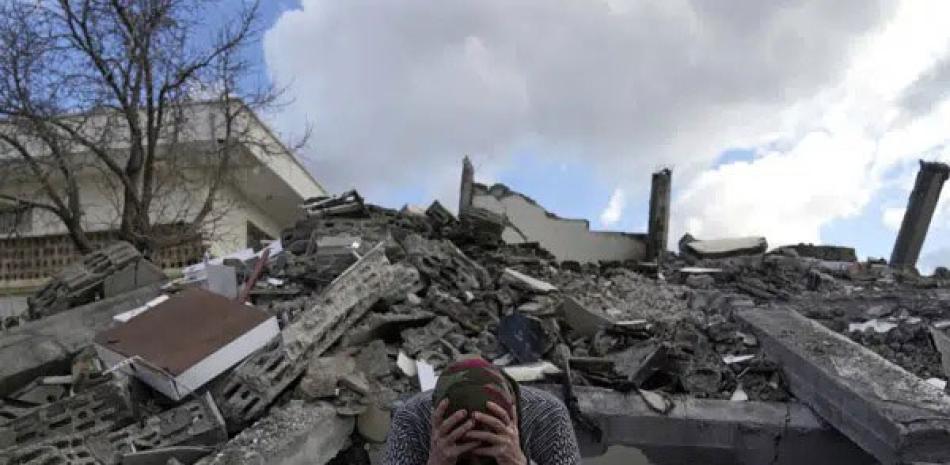 Una mujer sentada sobre los escombros de un edificio que se derrumbó por el sismo del lunes en Nurdagi, sur de Turquía, el martes 7 de febrero de 2023. AP