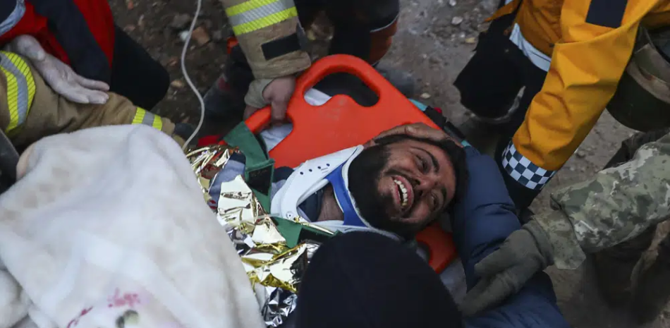 Rescatistas turcos llevan a Ergin Guzeloglan, de 36 años, a una ambulancia después de sacarlo de entre los escombros de un edificio derrumbado cinco días después de un terremoto en Hatay, en el sur de Turquía, la madrugada del sábado 11 de febrero de 2023. (AP Foto/Can Ozer